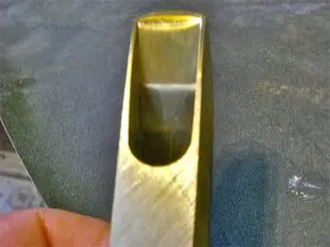 A person's hand holding a piece of brass.