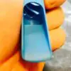 A hand holding a blue plastic object in front of the camera.