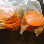 A pile of orange discs sitting in plastic bags.