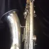 A silver saxophone sitting on top of a black floor.