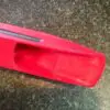 A red plastic box with a knife stuck in it.