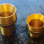 Two brass cups sitting on a table next to each other.