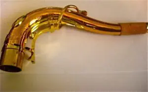 A gold colored saxophone laying on top of a white table.