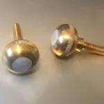 A pair of gold knobs with white numbers on them.