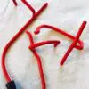 A red wire sculpture is laying on the ground.