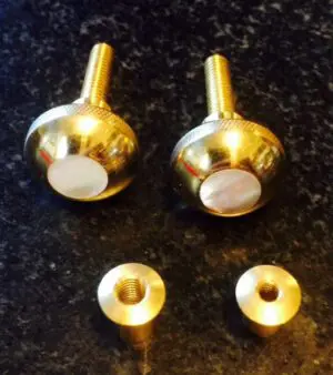 A pair of knobs and two brass washers on the floor.