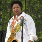 A man in a white shirt playing a saxophone.