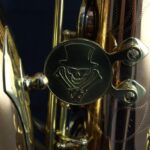 A close up of a gold saxophone with a hat on it.