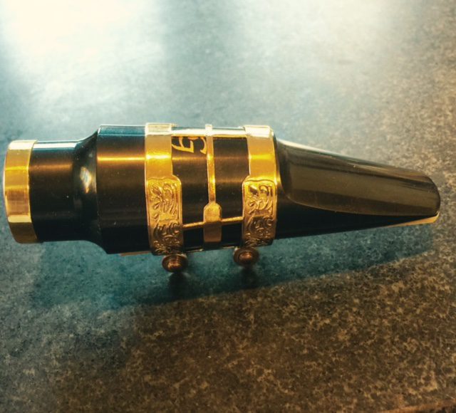 A black and gold SG Model Acrylic Jazz Tenor Mouthpiece on a table.