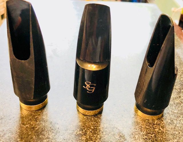 Three black and gold trumpets sitting on a table.