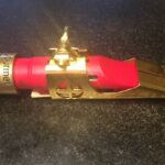 A red and gold Dragon's Tongue Delrin Mouthpiece on a table.